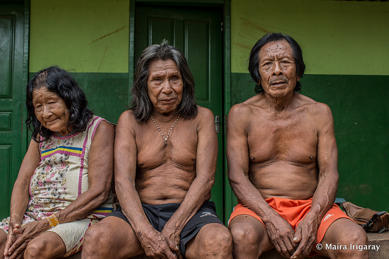 Three indigenous people sit on stoop in Altamira.